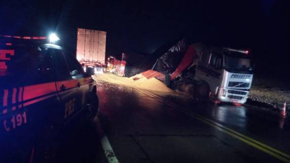 Acidente ocorreu na noite desta quinta-feira (04); apesar do tombamento da carreta, motoristas tiveram apenas ferimentos leves e foram liberados após atendimento médico.