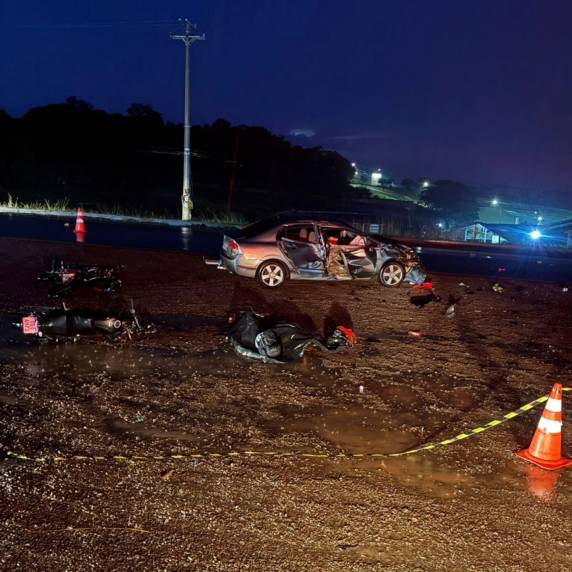 Colisão entre carro e motocicletas ocorreu no trevo de acesso ao município; terceira vítima foi socorrida em estado grave após possível aquaplanagem do veículo